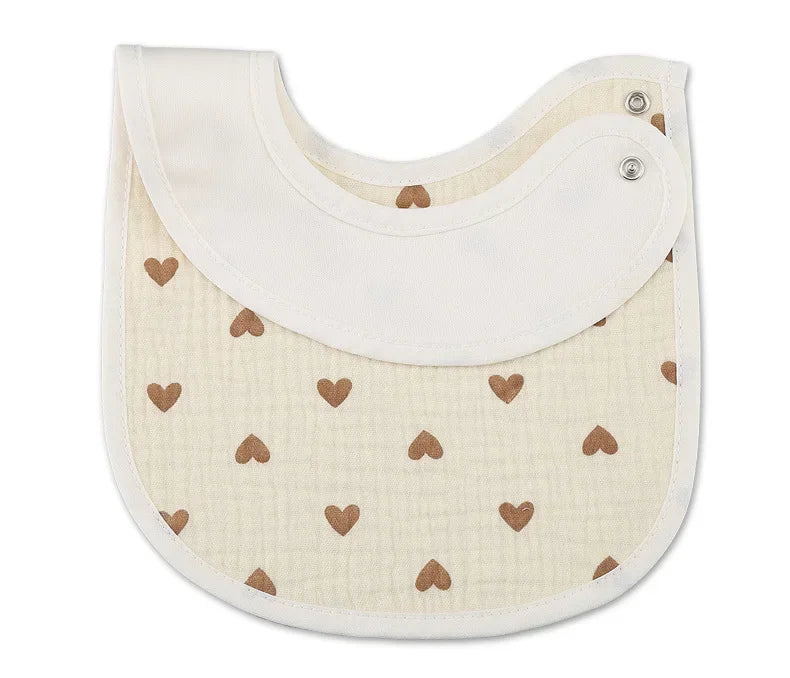 A beige baby bib adorned with small brown heart patterns, featuring a curved design and dual snap closures for an adjustable and secure fit.