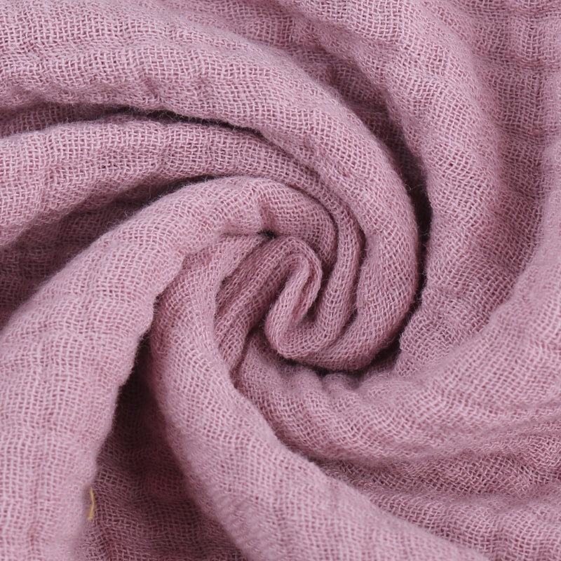 Extreme close-up of mauve baby towel fabric showing soft swirled texture and plush bamboo cotton blend material, highlighting the gentle draping and premium quality through natural light and shadow detail