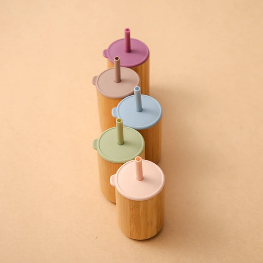 Elegant lineup of sustainable bamboo drinking cups with silicone straw lids in complementary pastel shades - dusty rose, cream, powder blue, sage green, and blush pink - arranged in a diagonal composition on neutral background, showcasing the collection's cohesive color palette and eco-friendly design