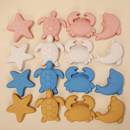 Complete collection of silicone beach molds arranged in four color rows - coral pink, cream, dusty blue, and mustard yellow - each featuring matching starfish, turtle, crab, and dolphin shapes, showcasing the full range of modern coastal designs