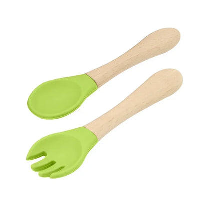 Set of natural wooden baby utensils featuring a spoon and fork with bright lime green silicone tips, combining eco-friendly wooden handles with soft-touch feeding ends for safe and comfortable baby mealtimes