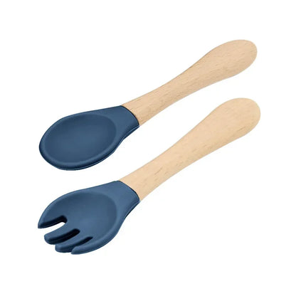 Set of natural wooden baby utensils featuring a spoon and fork with navy blue silicone tips, combining eco-friendly wooden handles with soft-touch feeding ends for safe infant dining