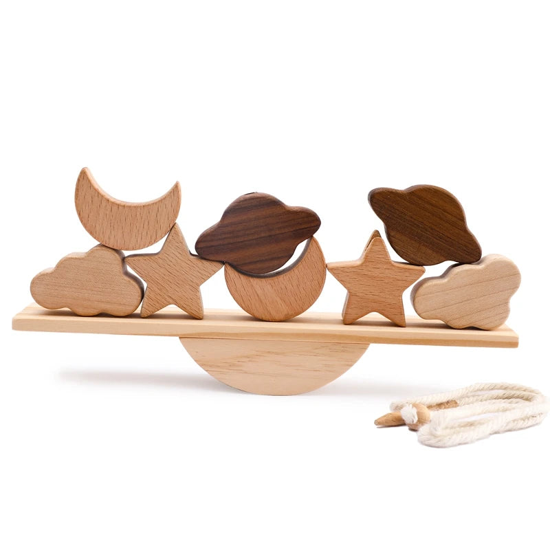 Natural wooden balance beam toy featuring interchangeable celestial-themed pieces including moon, stars, and clouds in mixed wood tones of beech and walnut, creating an enchanting balancing game photographed on white background with cotton string detail